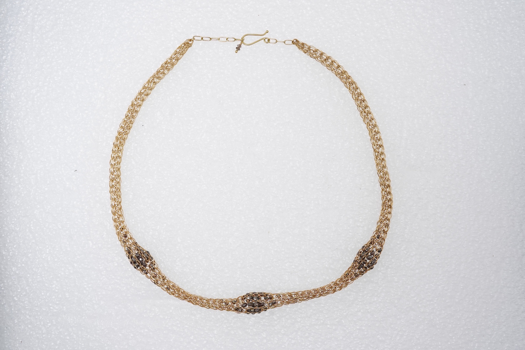 An 18ct gold and diamond necklace, composed of a woven tube of 18ct gold wire links, three sections threaded with brown diamond beads, length approximately 45cm, British hallmarks, sponsor's mark TJH, gross weight approx